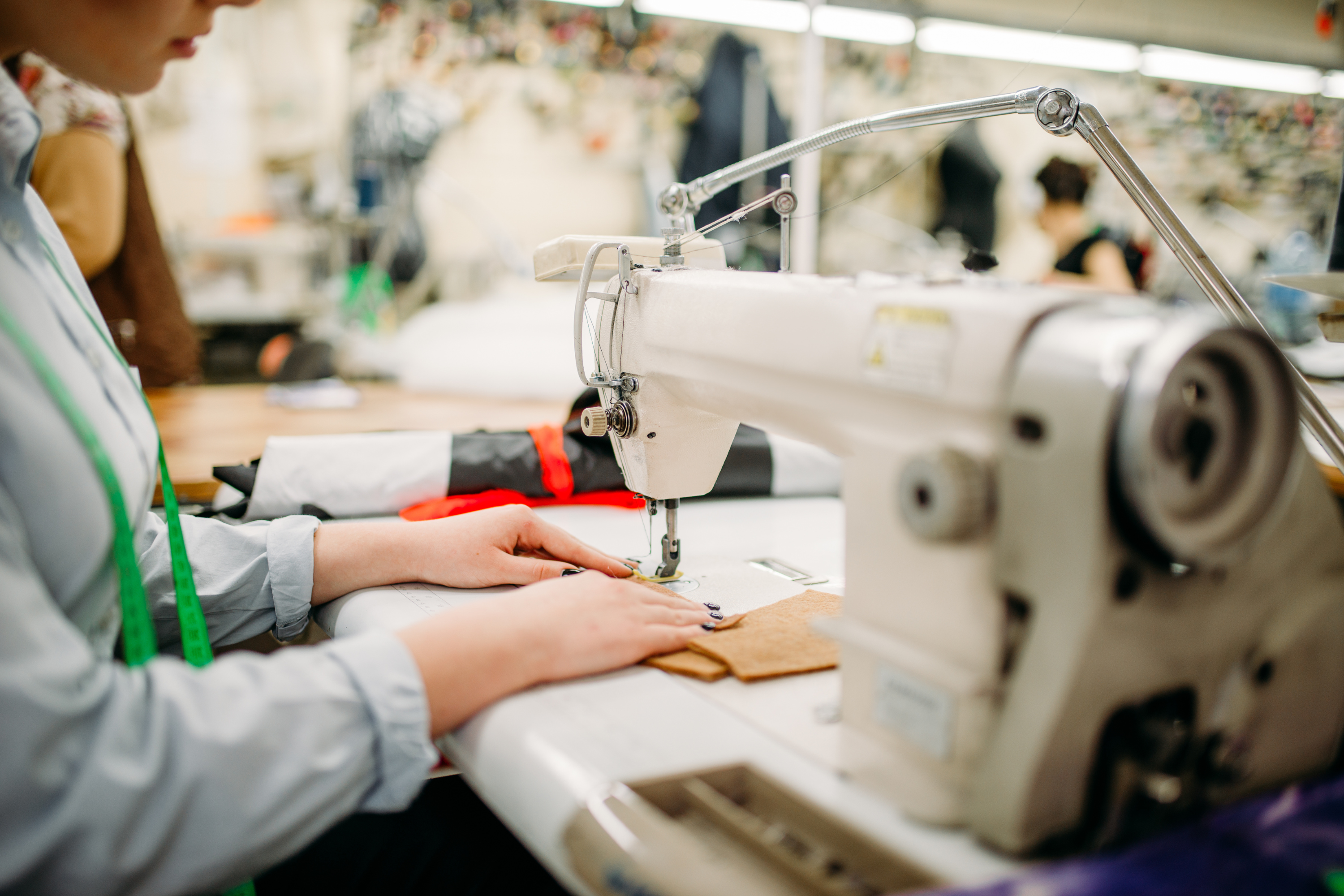 Person working on a sewing machine in a clothing factory.